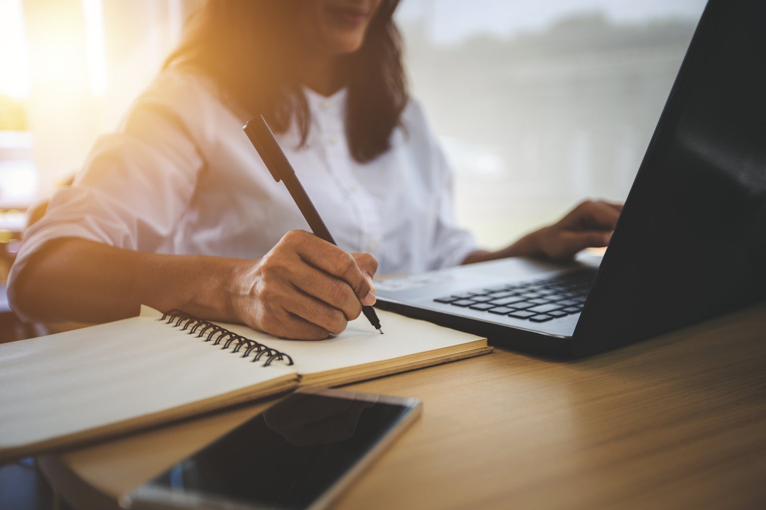 young woman on laptop and taking notes