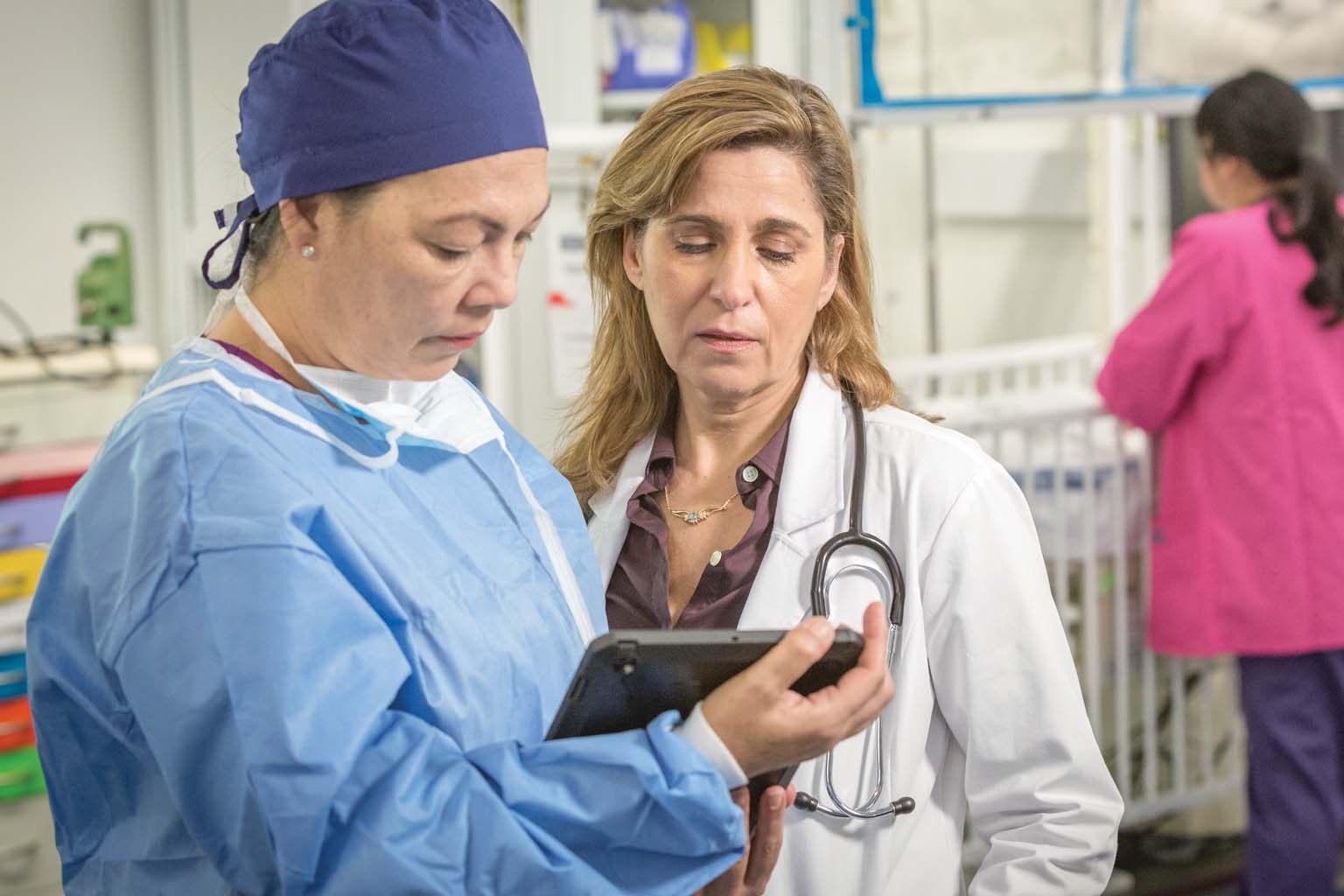 surgeon and doctory looking at tablet with nurse in background