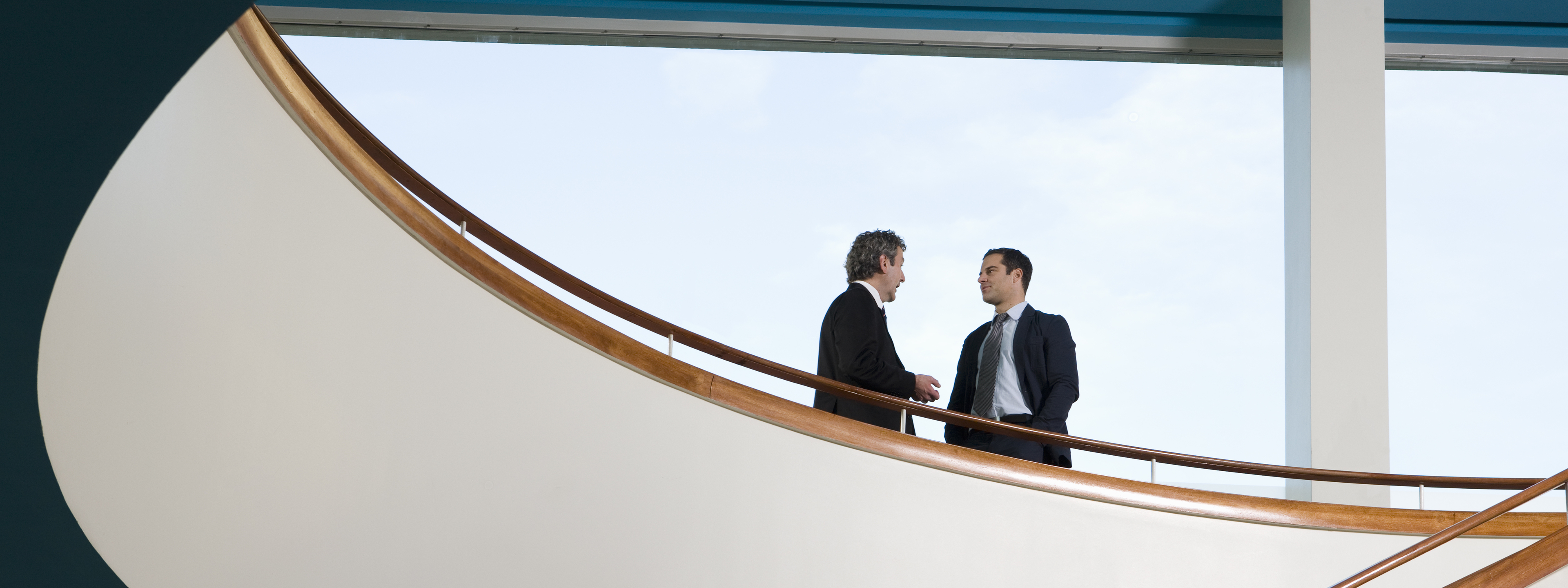 Two businessmen standing on a balcony and talking 