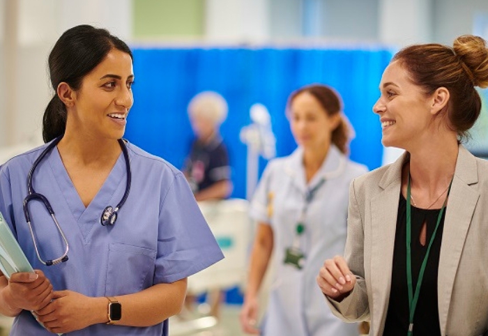 Hospital admin and nurse smiling and talking to eachother