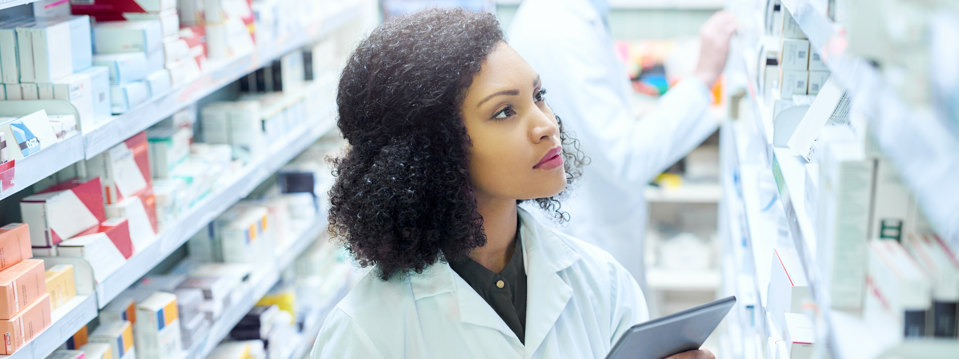Female pharmacist in drug storage aisle
