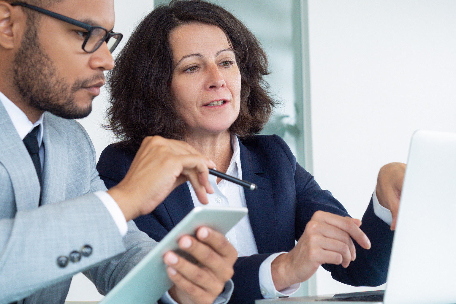 Healthcare professional using laptop to work alongside a colleague