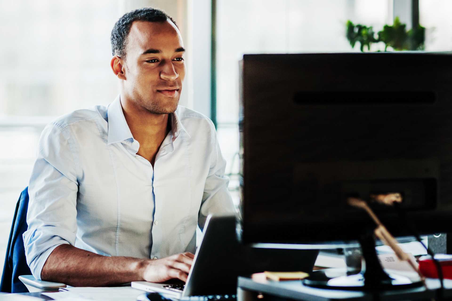 Man works at laptop with second screen