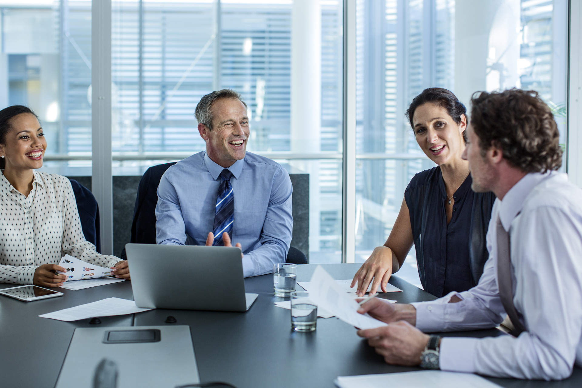 Happy business professionals discussing at conference table in office.