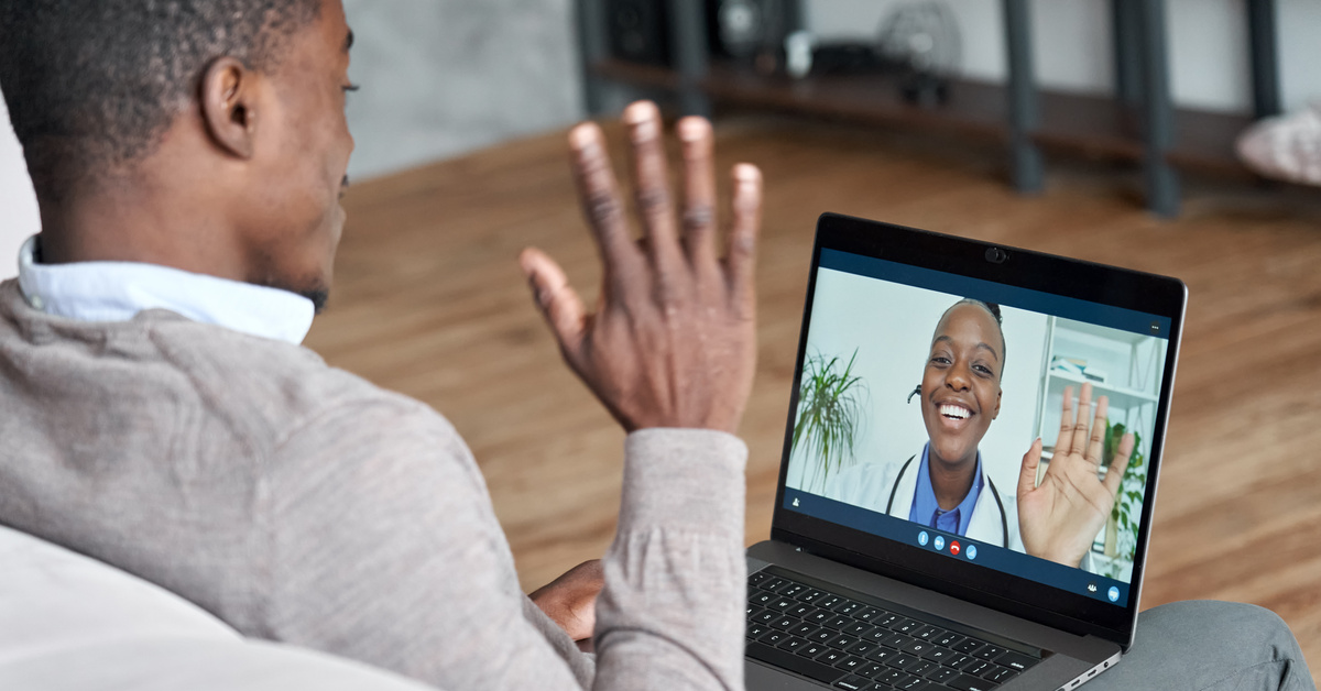 Clinician virtually consulting young man during online appointment on laptop at home