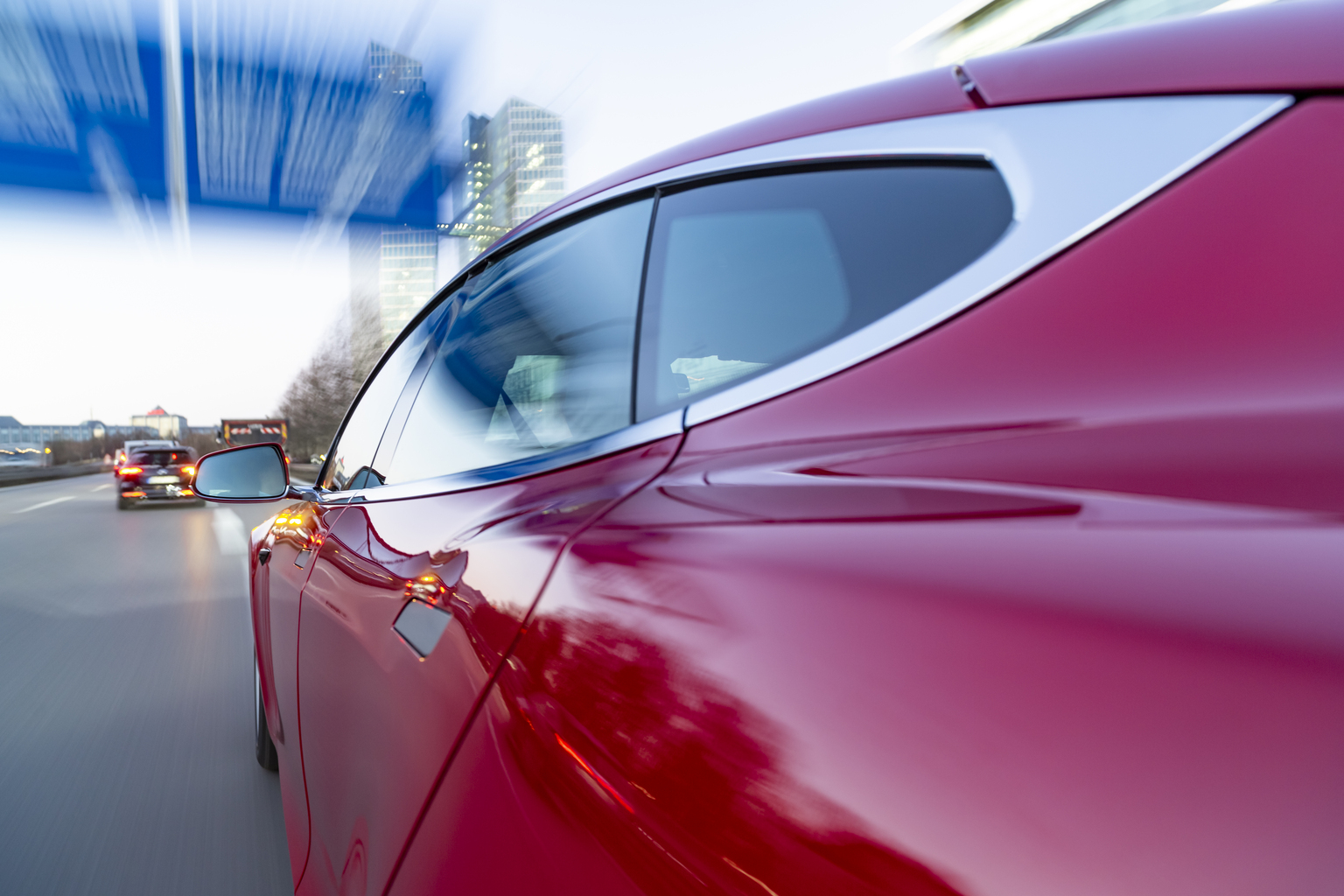 Electric powered US car drives while dawn on German Autobahn A9 into the city of Munich