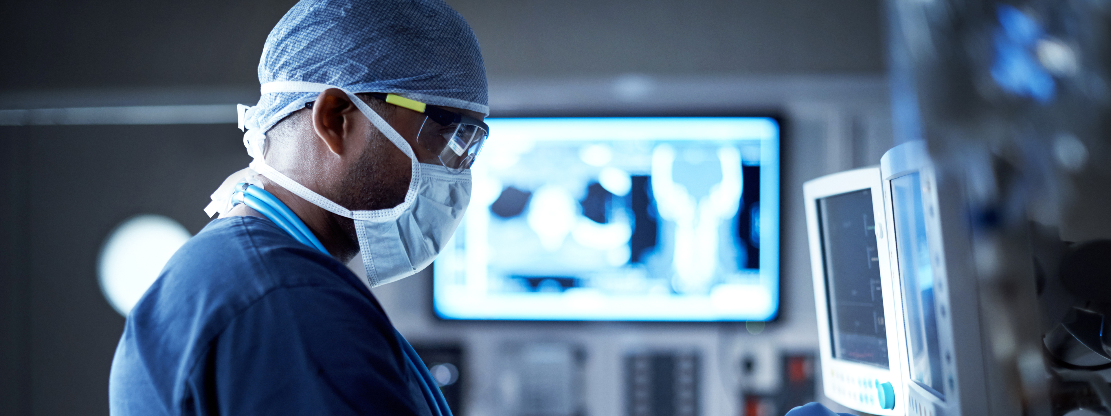 African male doctor monitors patient's vital signs on screen.