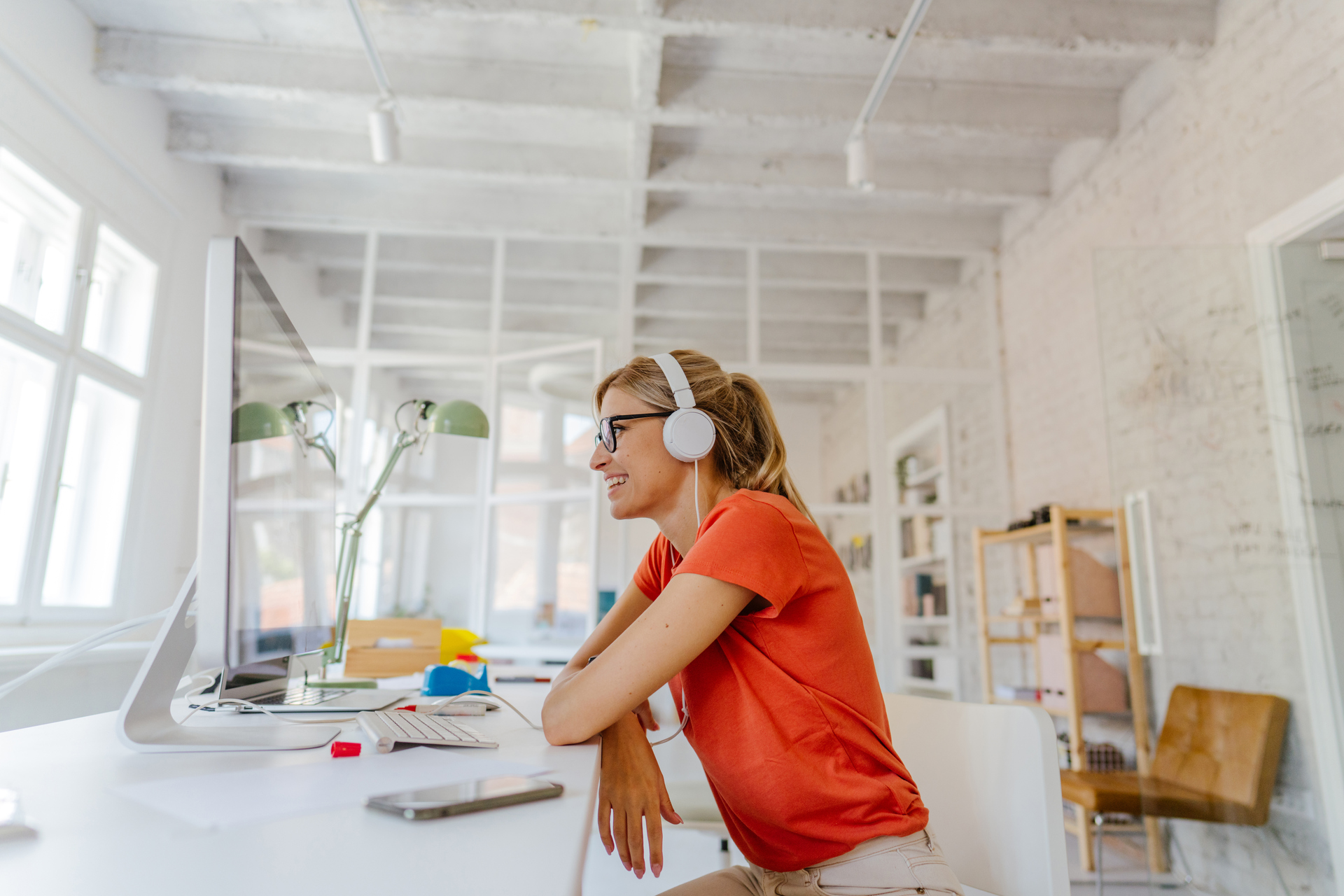 Young woman wearing headphones while using laptop on desk at home