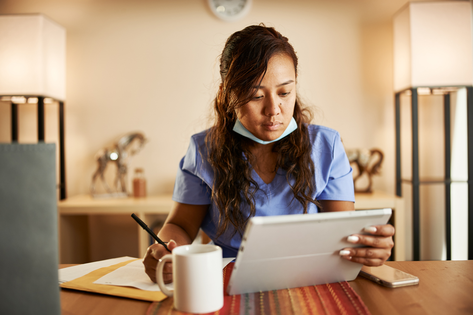 Nurse working from home doing paperwork and using tablet