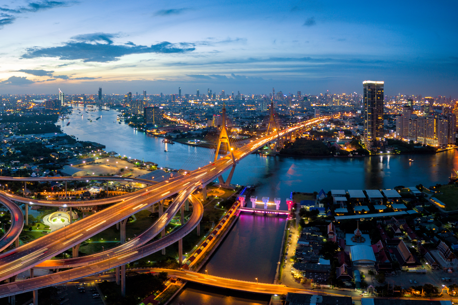 Aerial view of Bhumibol suspension bridge cross over Chao Phraya River in Bangkok city with car on the bridge at sunset sky and clouds in Bangkok Thailand.