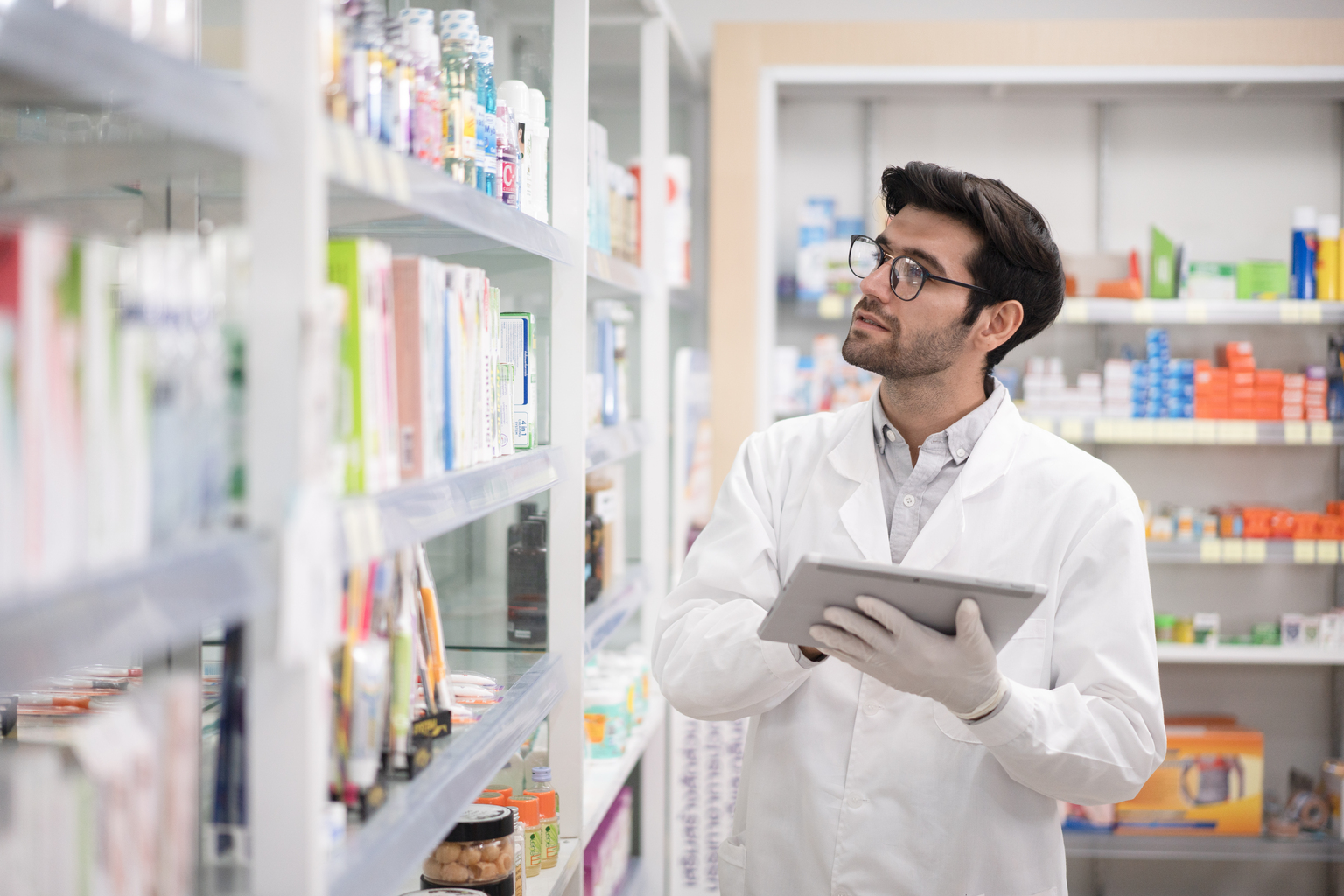 White man using a digital tablet to take inventory in a pharmacy.