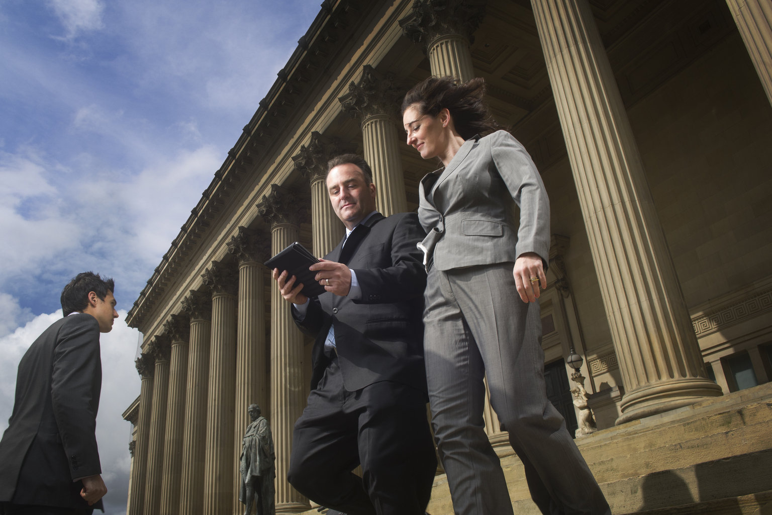 Two people in suits walking, discussing who needs to file BOI reports and what information is needed to file