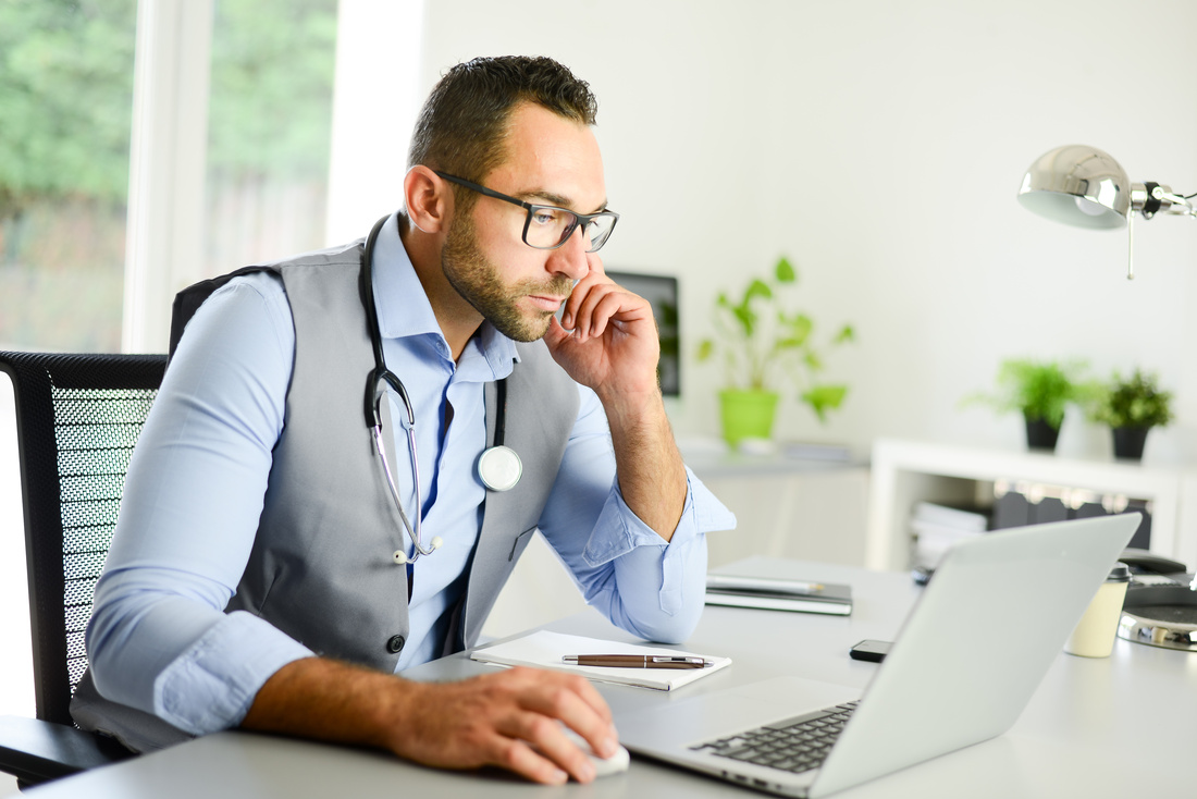 Male doctor on laptop in clinic office