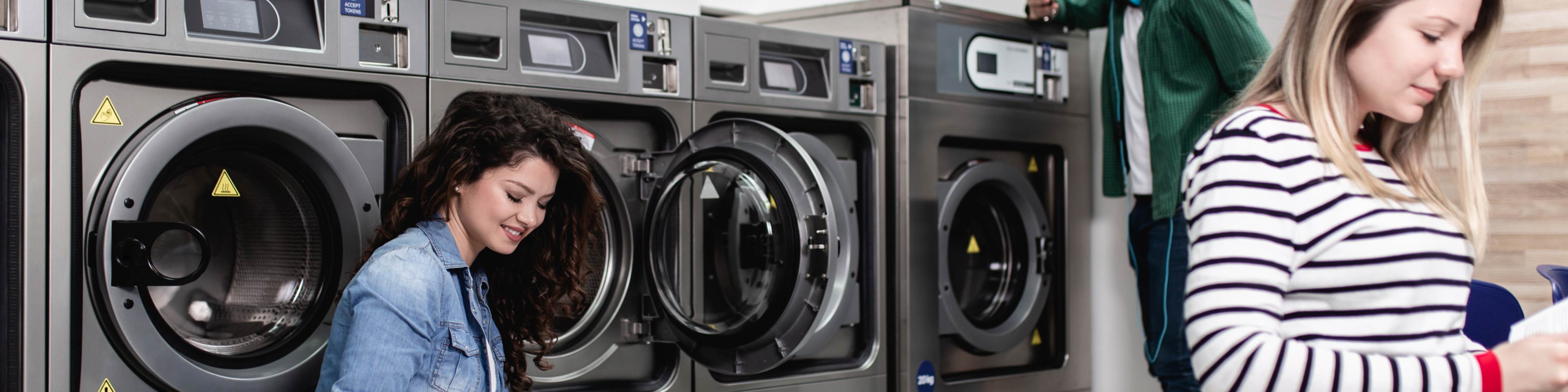 two women standing in front of washing machines