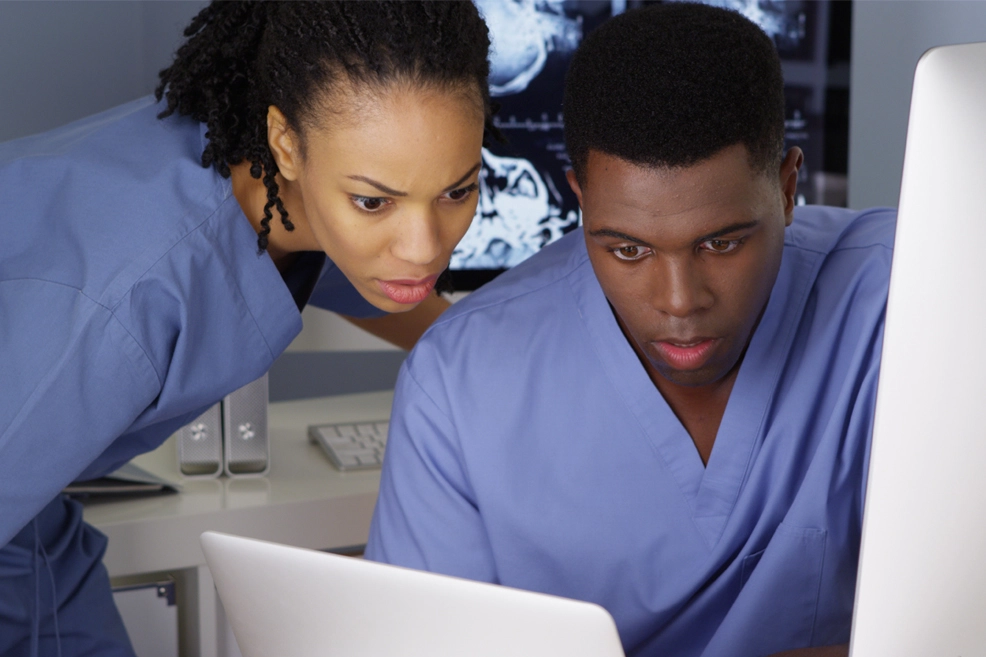 Two young nurses working together on multiple computers