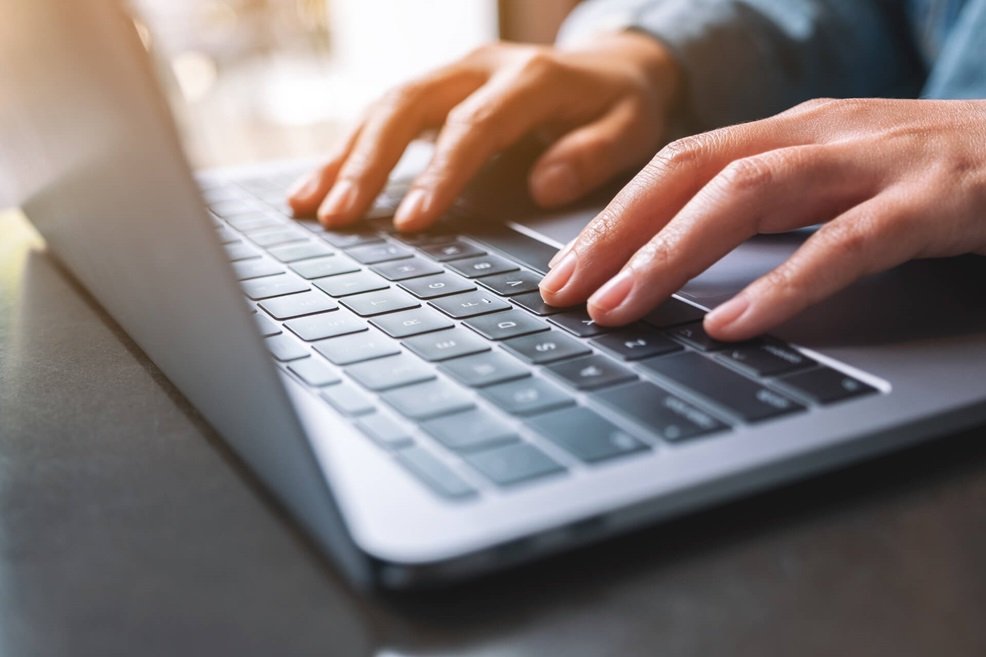 A man's hands on a laptop keyboard using scanning software and computer vision technology to automatically populate tax data