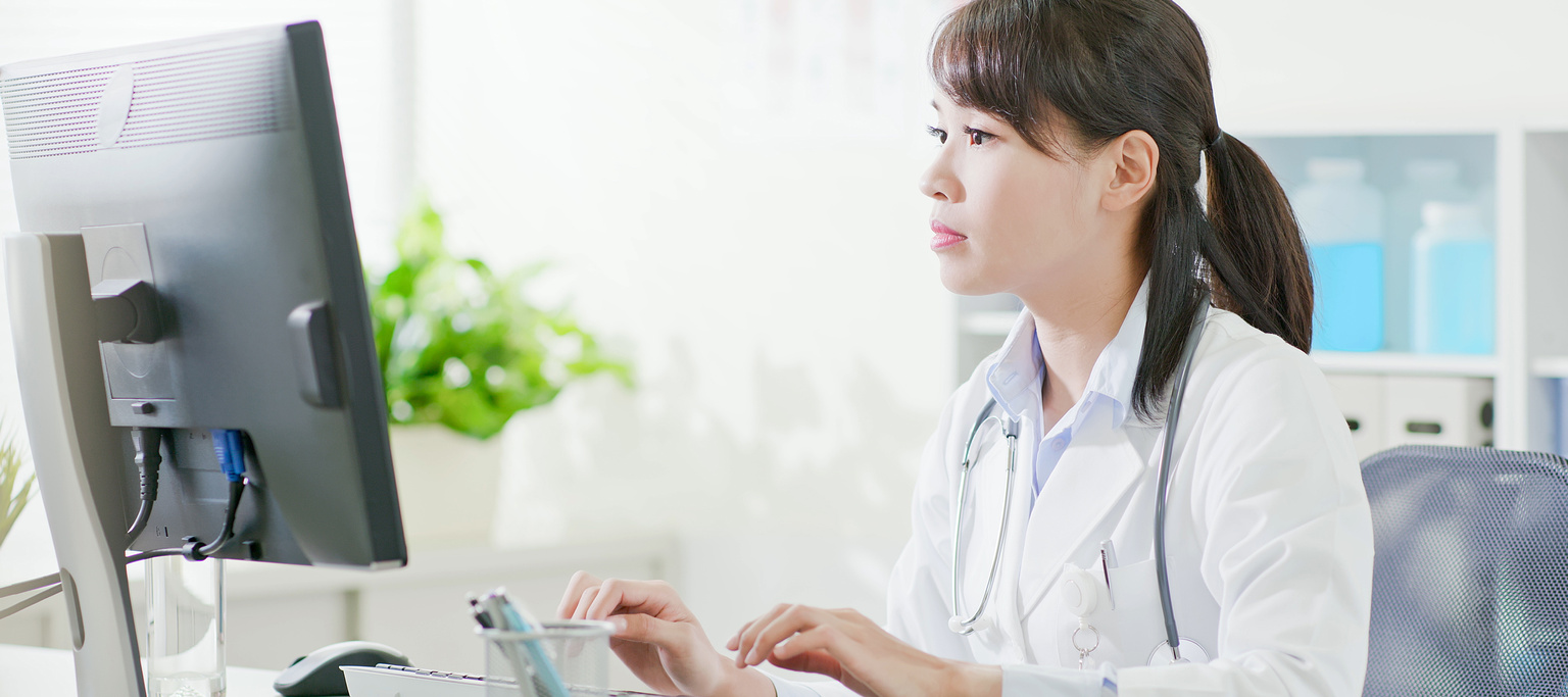 Doctor typing on desktop computer