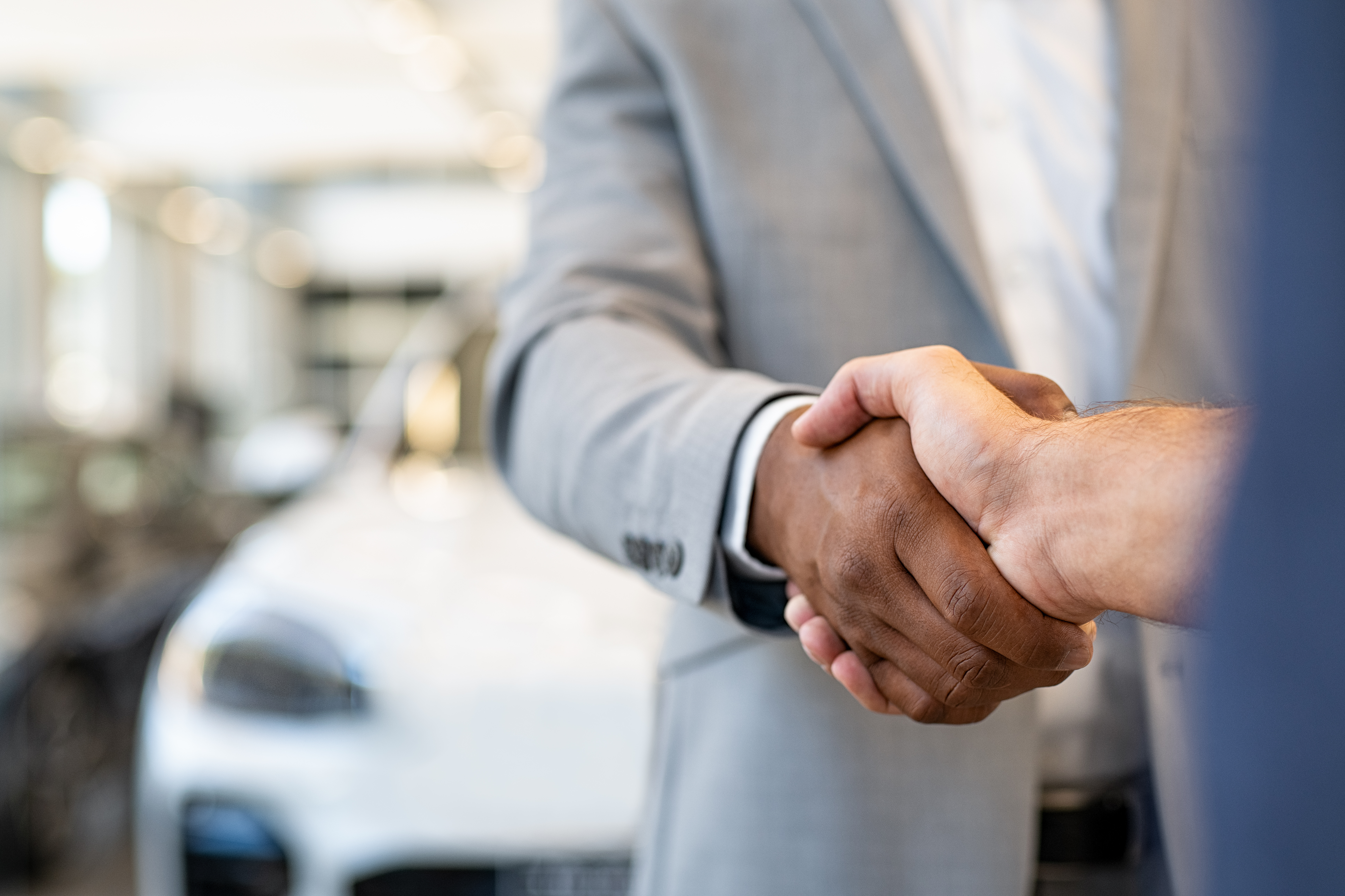  Car salesman and client handshake