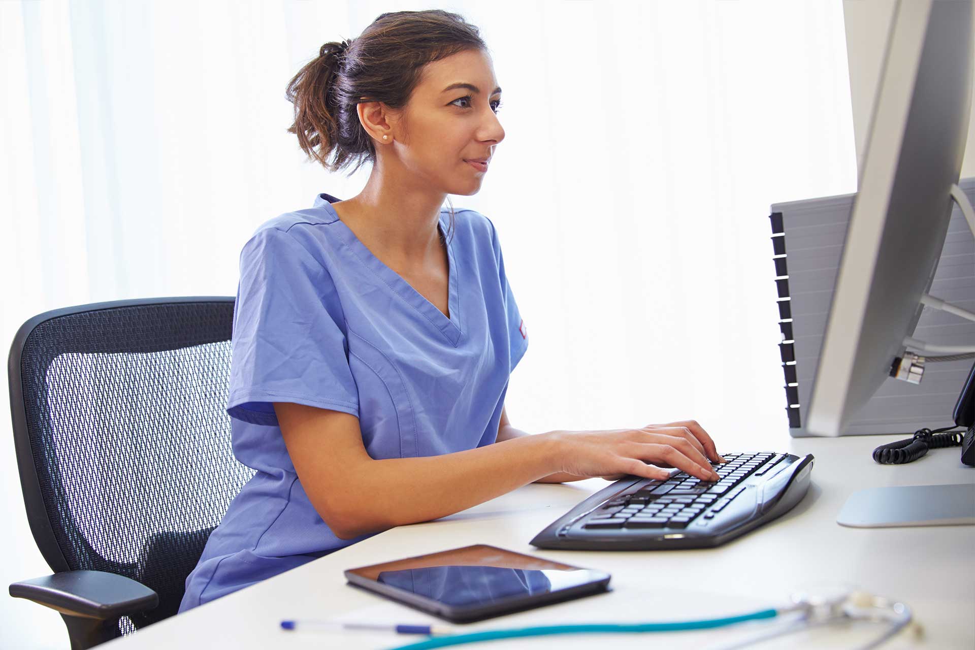 Nurse sitting at computer at desk