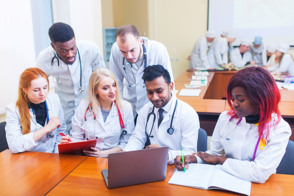 A mixed-race group of medical students in front of a laptop
