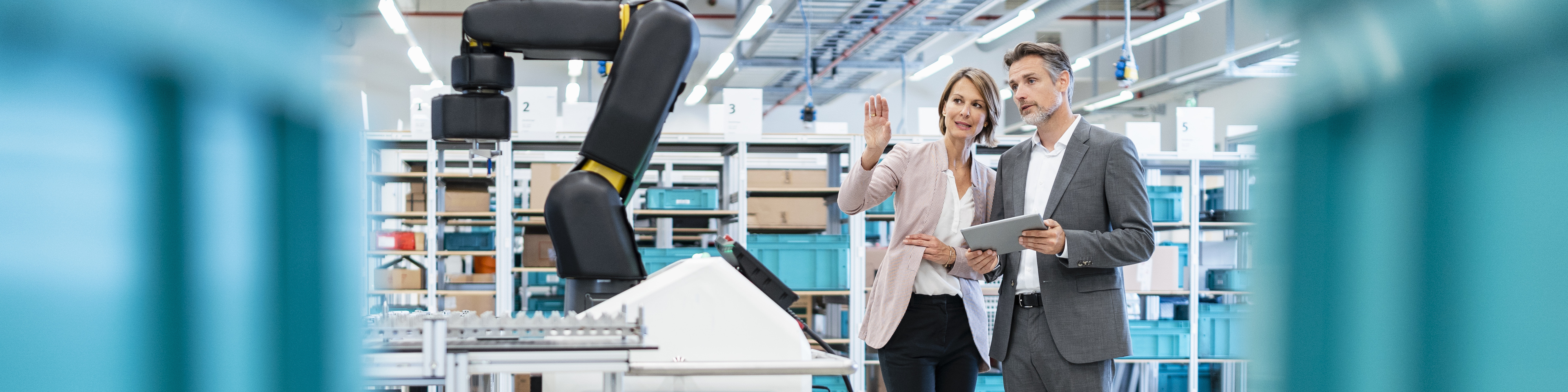 Businessman and businesswoman talking in a modern factory hall.