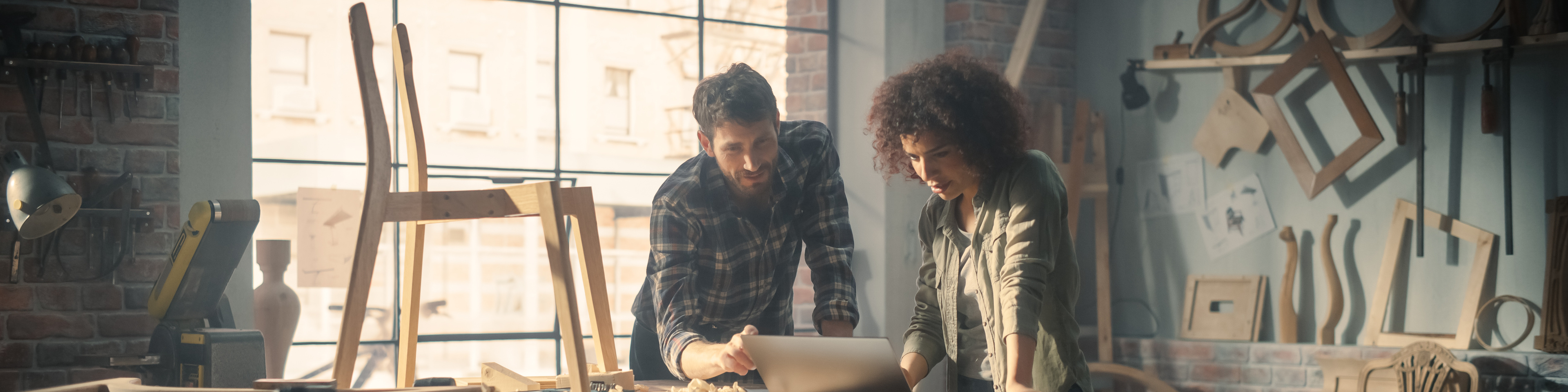 Young business couple using laptop in furniture studio