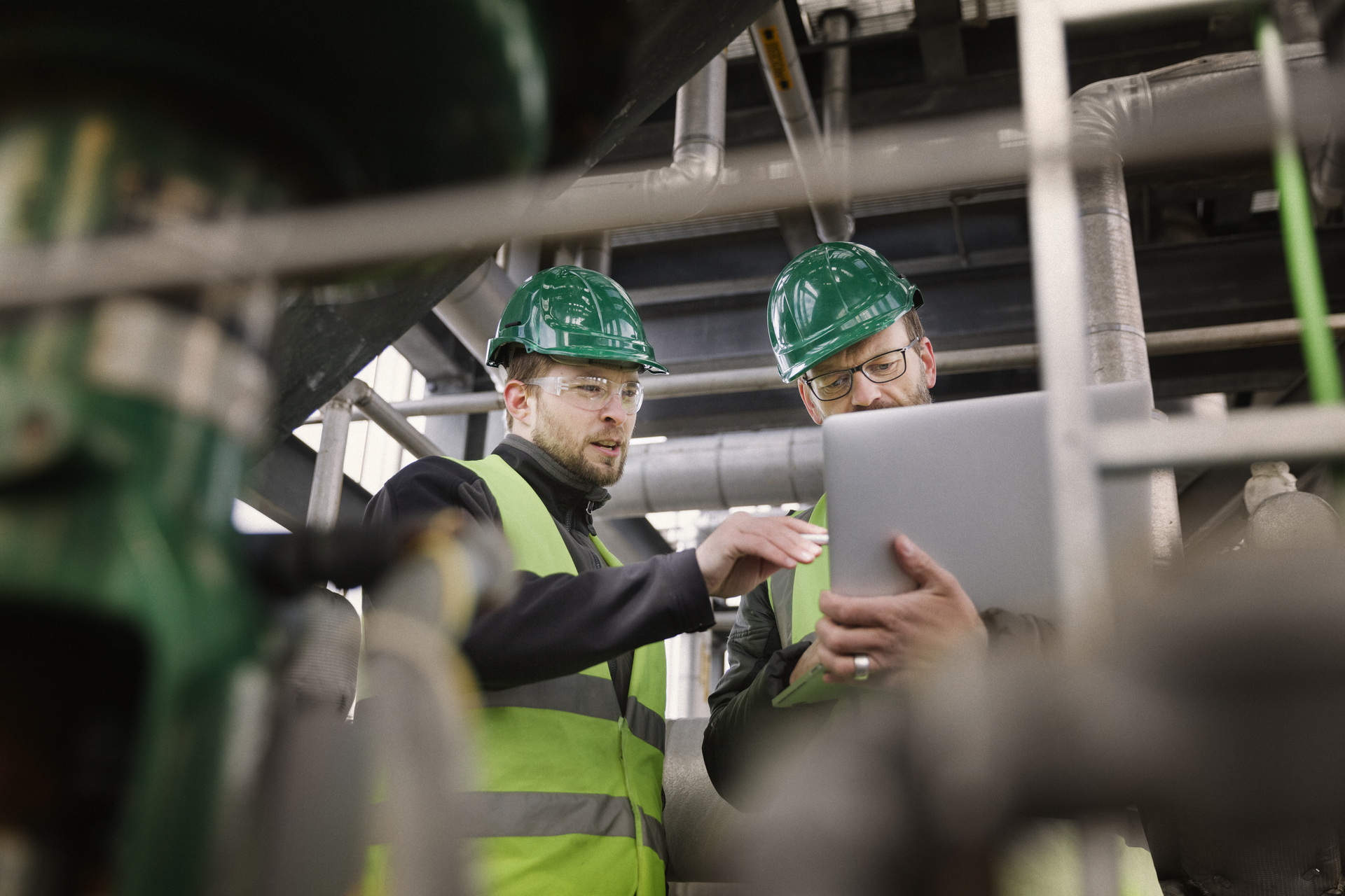 Manual workers discussing while using laptop at factory